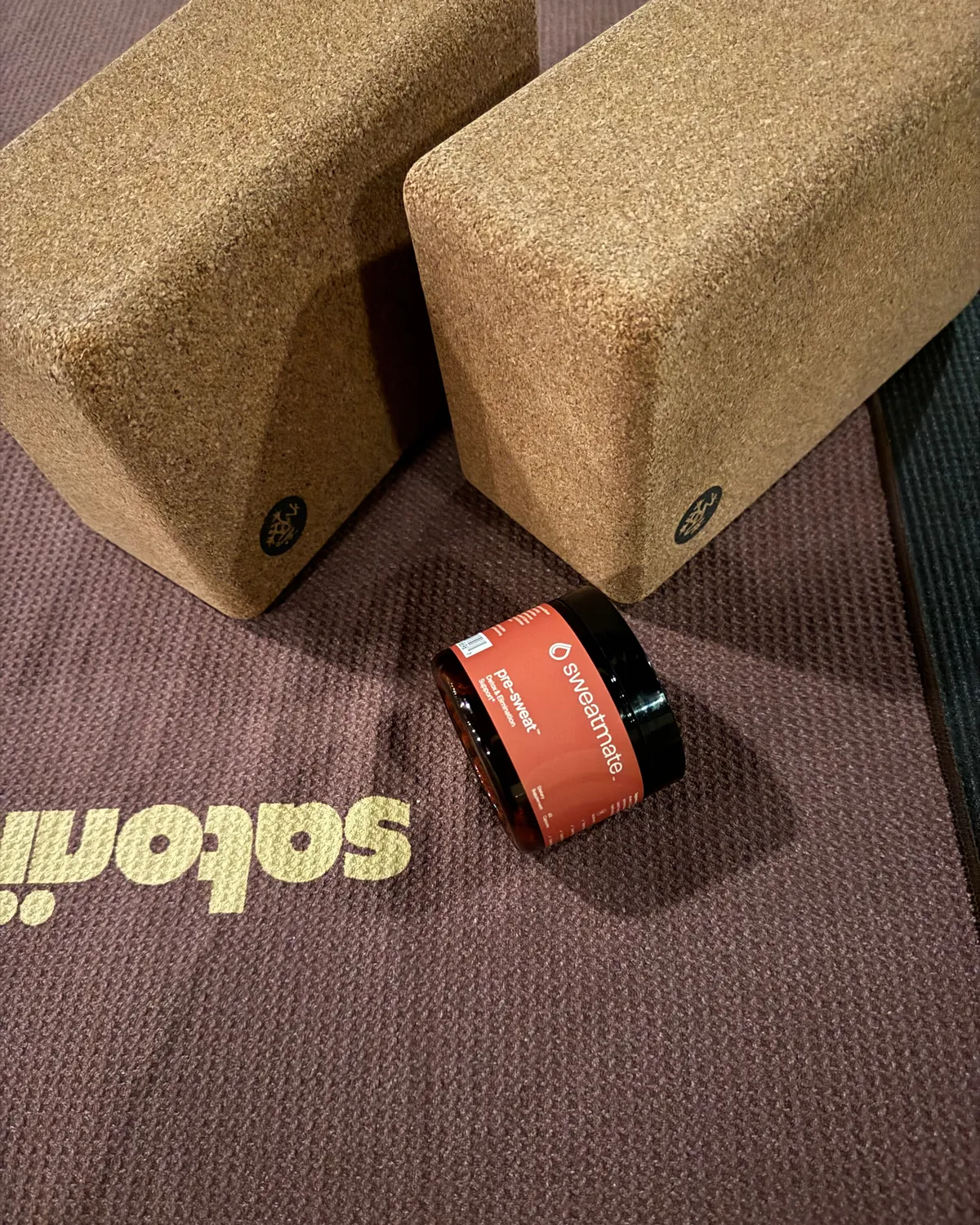 A Sweatmate jar beside cork yoga blocks on a yoga mat